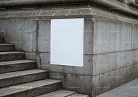 Blank white poster on urban stone wall near stairs