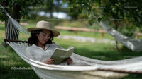 Woman Relaxing in a Hammock Reading a Book in Green Outdoors