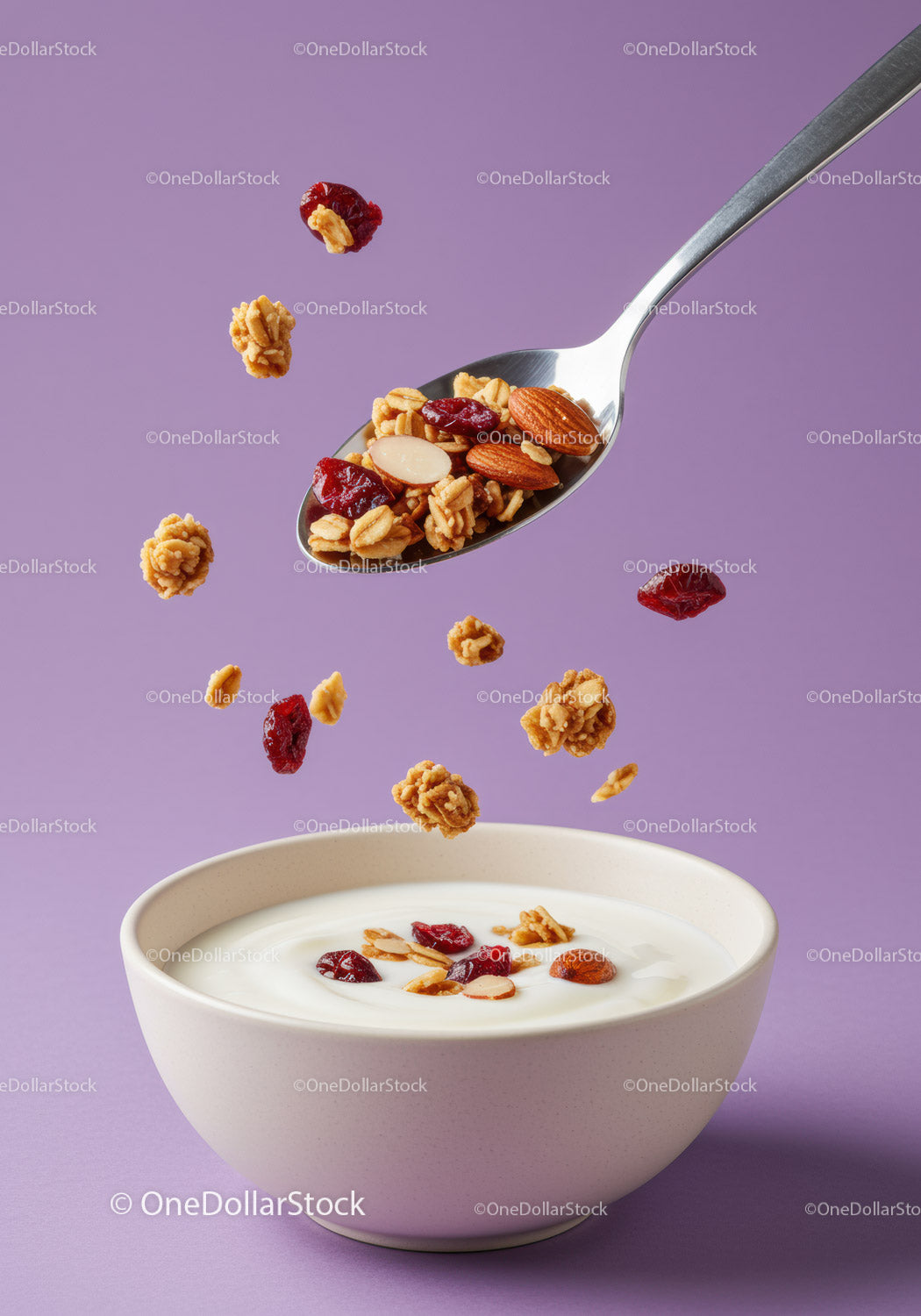 Granola i jagody wpadające do kremowej miski jogurtowej