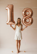 Young woman celebrating 18th birthday with rose gold balloons