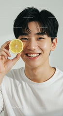 Young Man Smiling Holding Lemon Slice in Bright Studio Portrait