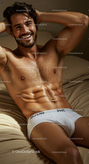 Smiling muscular man relaxing on bed in white underwear