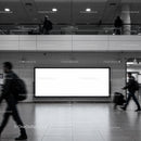 Busy urban commuters passing blank billboard in transit hub