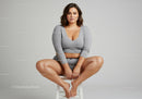 Confident Woman Sitting Cross-Legged in Casual Gray Outfit