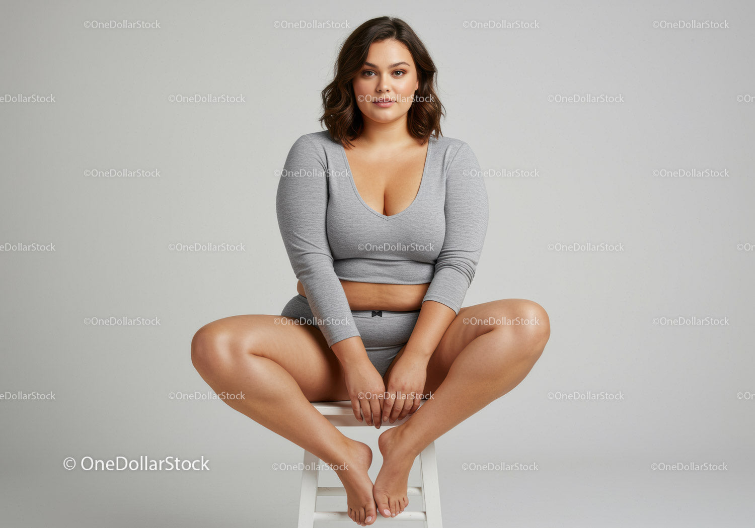 Confident Woman Sitting Cross-Legged in Casual Gray Outfit
