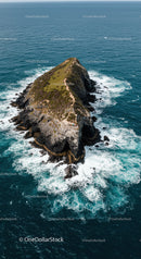 Dramatic Rocky Island Surrounded by Ocean Waves Aerial View