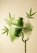 Green glass bottle surrounded by bamboo and green powder