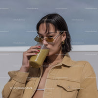 Young Woman Drinking Smoothie Wearing Sunglasses and Summer Clothing