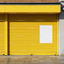 Bright yellow metal shutter with blank white poster