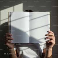 Person Holding Open Blank Book with Window Shadows
