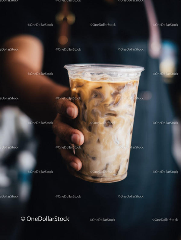 Iced Coffee in Hand with Creamy Swirls in a Clear Cup