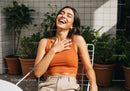 Happy Young Woman Laughing Outdoors on Stylish Chair with Garden Background