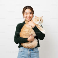 Smiling woman holding fluffy cream cat indoors