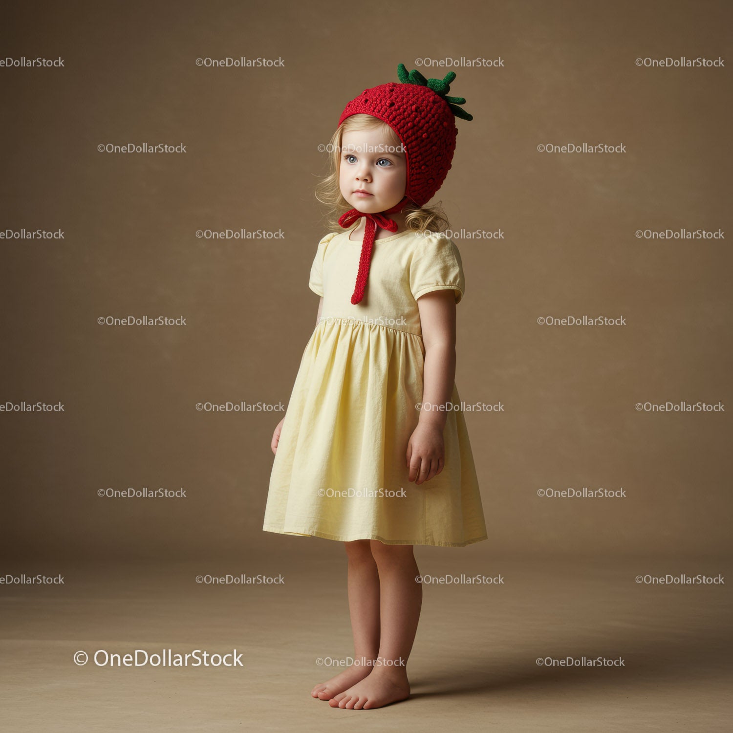 Young girl wearing strawberry hat and pale yellow dress