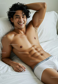 Smiling young man relaxing shirtless on white bed