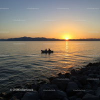 Serene Sunset Over Lake With Small Boat and Mountain Silhouette