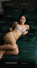 Smiling Woman Relaxing on Dark Green Bed at Home