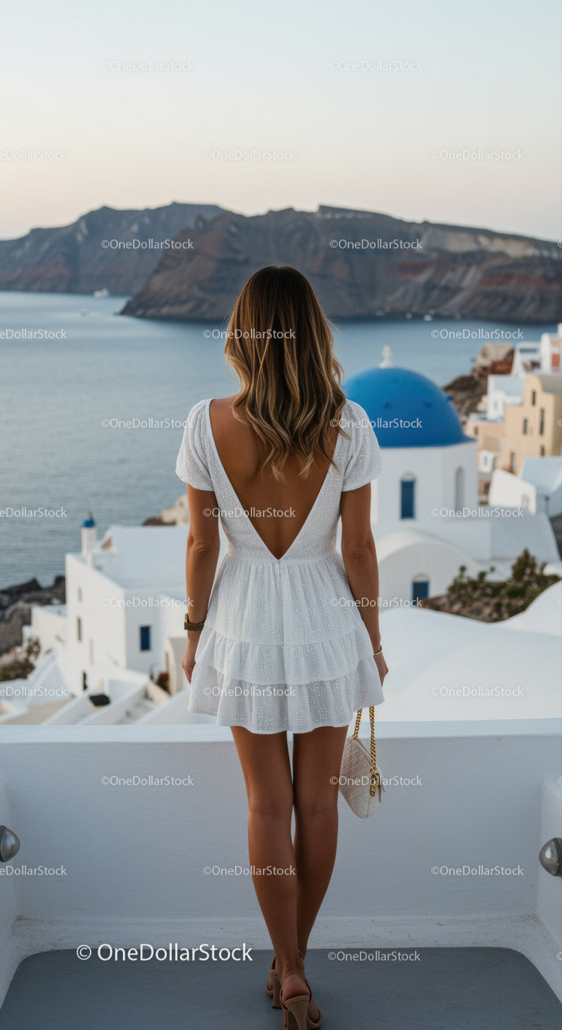 Kobieta w białej sukni podziwiająca widok na morze Santorini