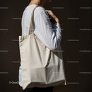 Person carrying blank canvas tote bag on shoulder