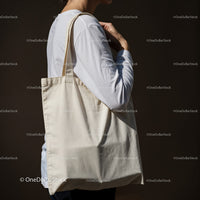 Person carrying blank canvas tote bag on shoulder