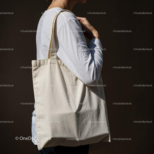Person carrying blank canvas tote bag on shoulder JPG Mockup Image