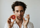 Man with Green Eyes Holding Grapefruit in Studio Portrait