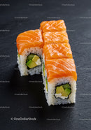 Fresh salmon avocado sushi rolls on black slate