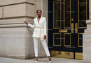 Elegant woman in white suit leaning on building corner