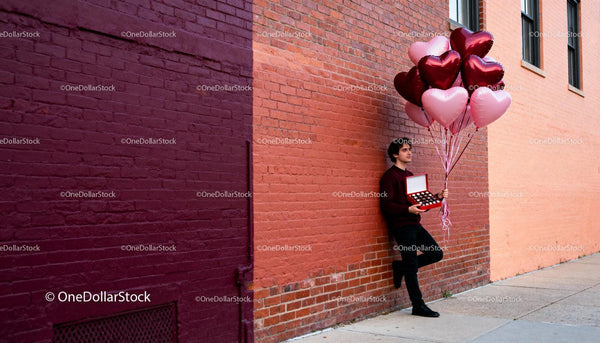 Man holding heart balloons and gift box on city street