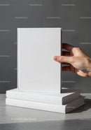Hand holding blank white book with two books stacked