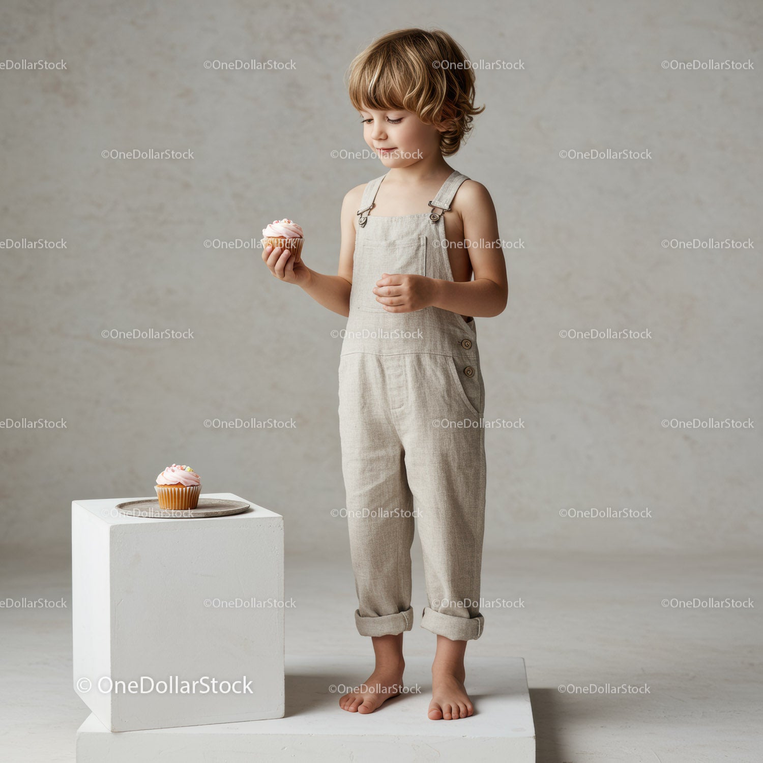 Child in neutral outfit holding a frosted cupcake