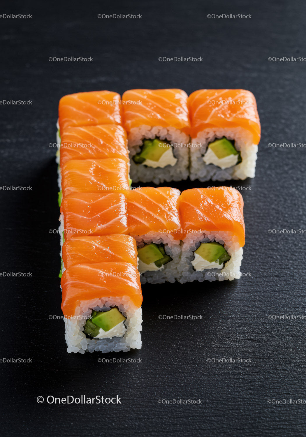 Fresh salmon sushi rolls arranged on black slate