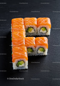 Fresh salmon sushi rolls arranged on black slate