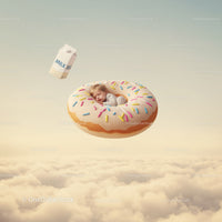 Sleeping baby nestled inside giant sprinkled donut above clouds