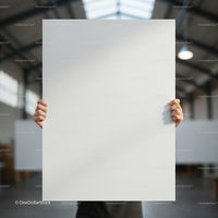 Person holding blank white poster in industrial space