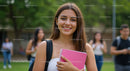 Happy Female College Student Outdoors with Pink Notebook