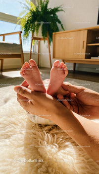 Parent Holding Newborn Baby Feet in Warm Sunlight