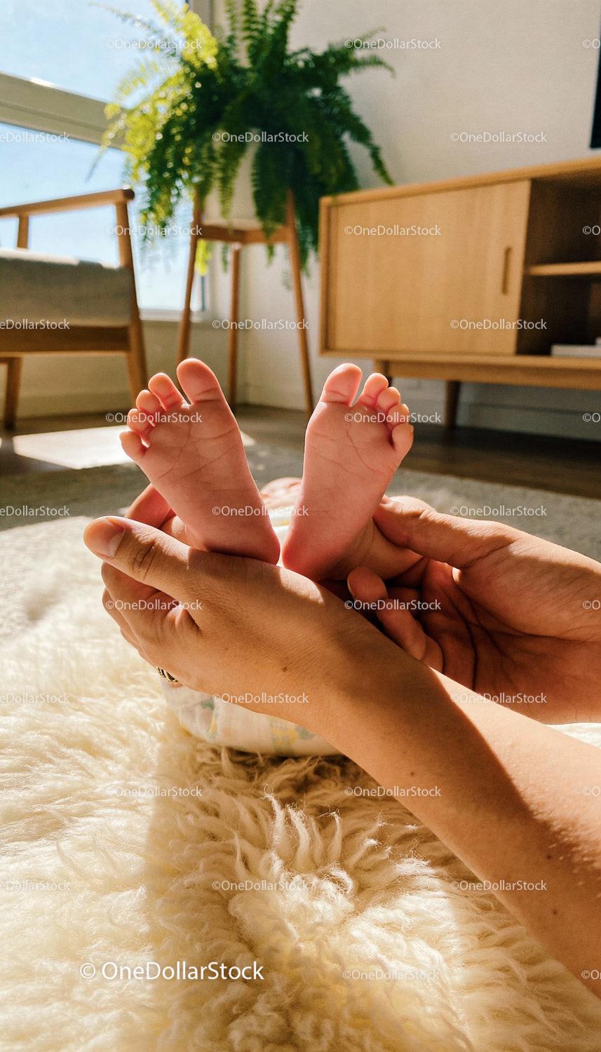 Parent Holding Newborn Baby Feet in Warm Sunlight