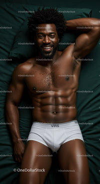 Smiling muscular man relaxing on dark green bed sheets