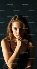 Thoughtful young woman with hand near face in low light