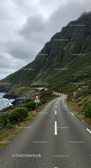 Mountain Road Winding through Lush Green Hills and Rocky Cliffs