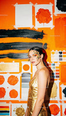 Woman in gold dress with creative makeup against art wall