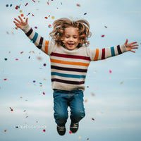 Joyful child jumping with colorful confetti outdoors