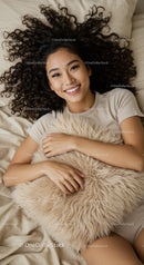 Smiling woman with curly hair lying on bed with soft pillow