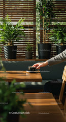 Hand Holding Coffee Cup in a Cozy Cafe Surrounded by Plants