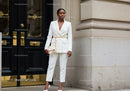 Confident woman in white pantsuit standing by elegant door