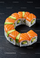 Fresh salmon and avocado sushi roll on black slate