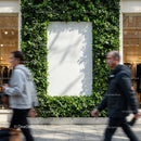 Urban green wall framing empty white poster in shopping mall