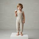 Little child holding cupcake in beige overalls