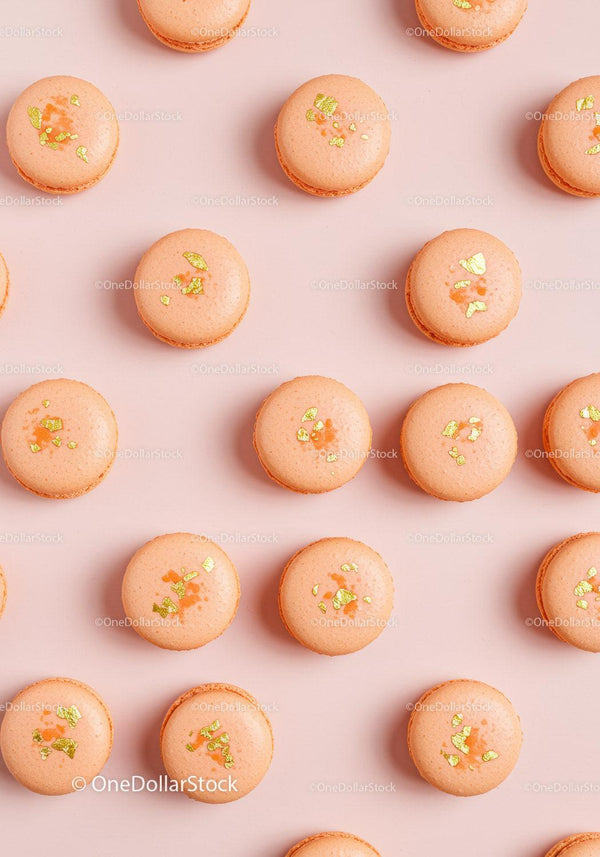 Elegant orange macarons with gold flakes on pink background